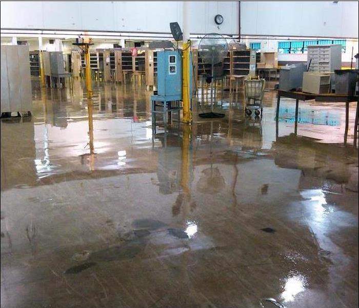 water reflecting off warehouse concrete floor with metal stands and equipment